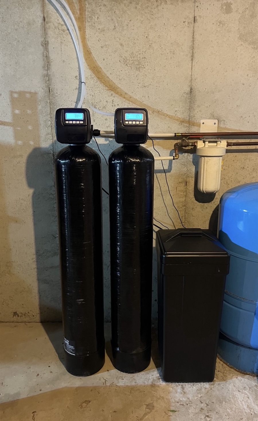 Iron filter and water softener side by side, each with its own digital valve, next to a pre-filter and well pressure tank
